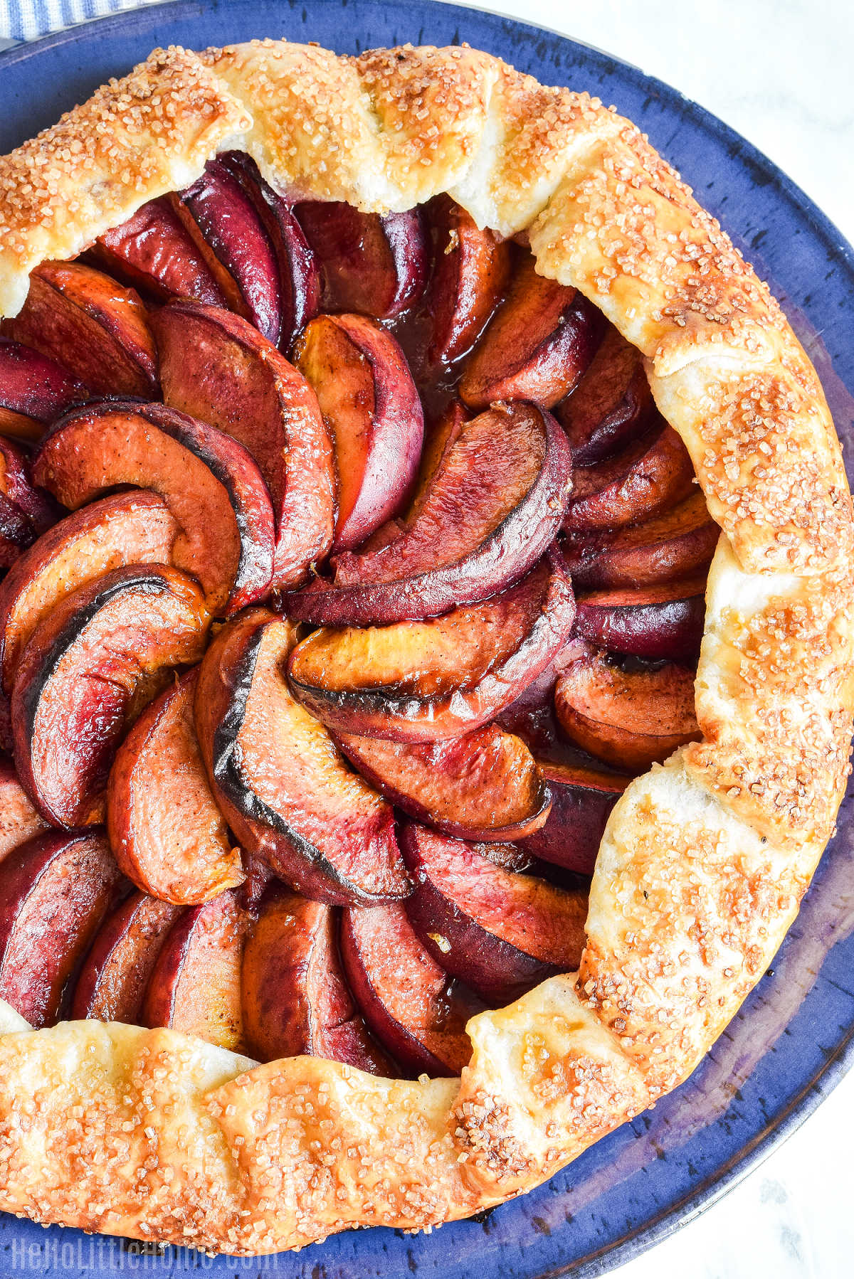 A rustic peach pie served on a blue plate.