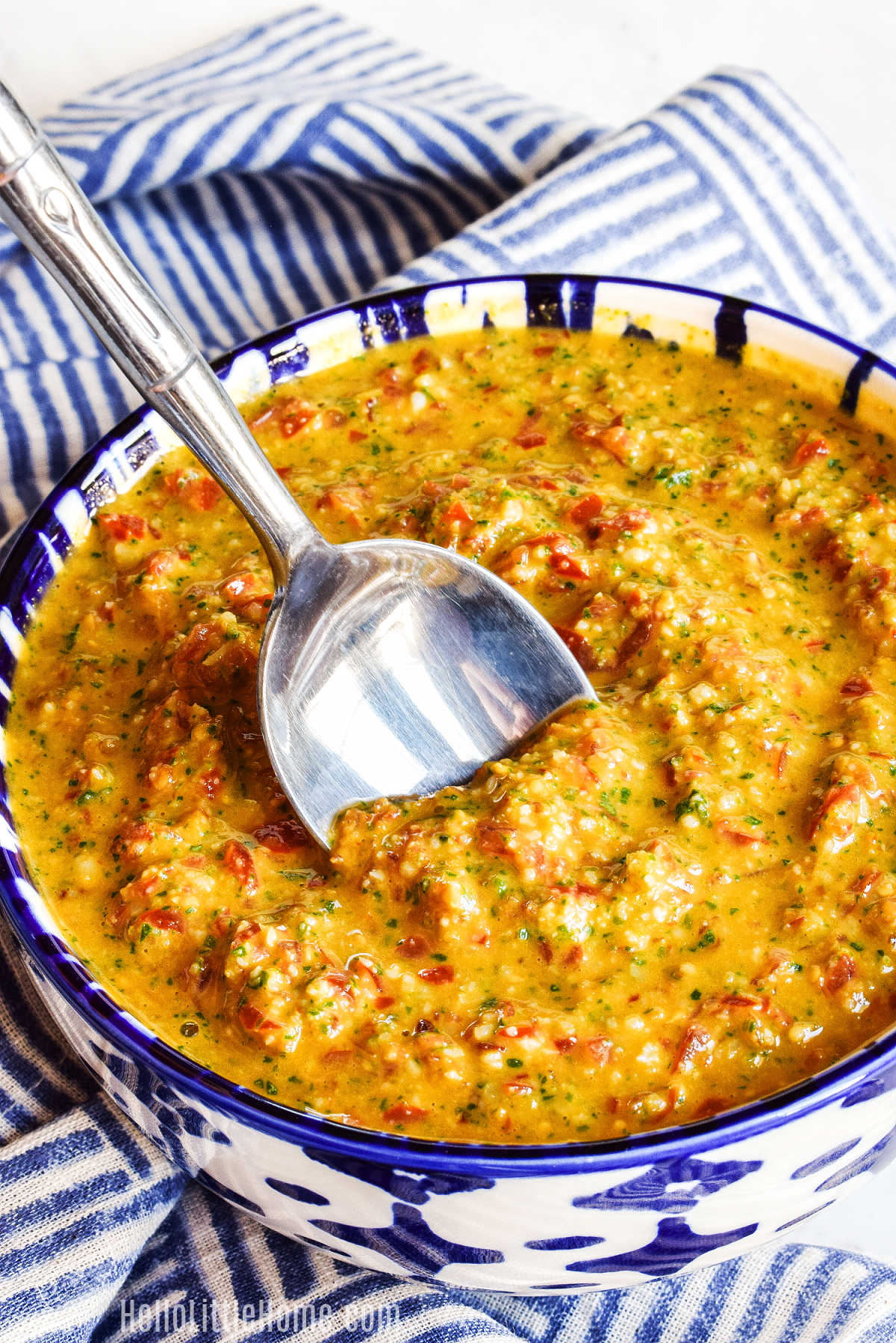A spoon stirring a bowl of Sicilian Pesto Sauce.