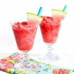 Two Watermelon Slushies and a patterned napkin on a marble counter.