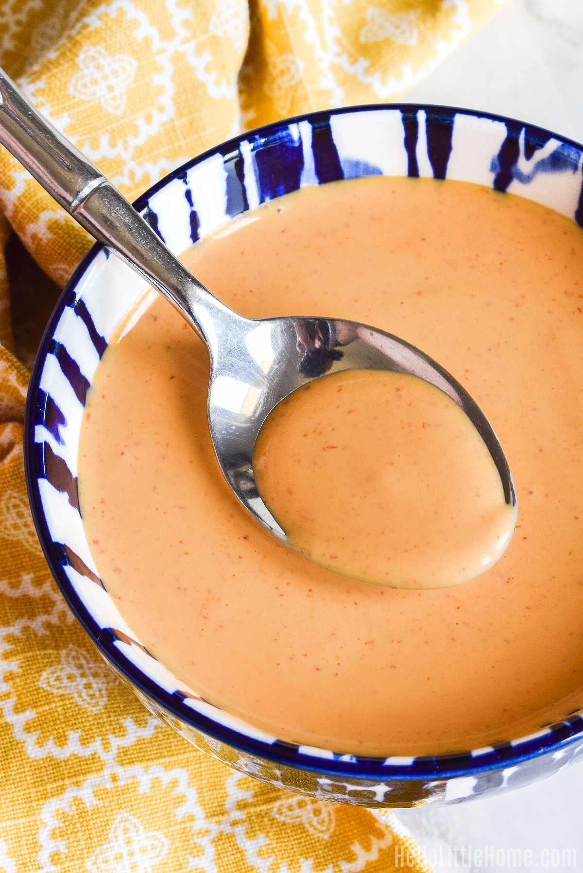 A spoon in a bowl of the finished Mayo and Sriracha Sauce.
