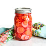 Pickled Carrots and Radishes served in a mason jar on a marble counter.