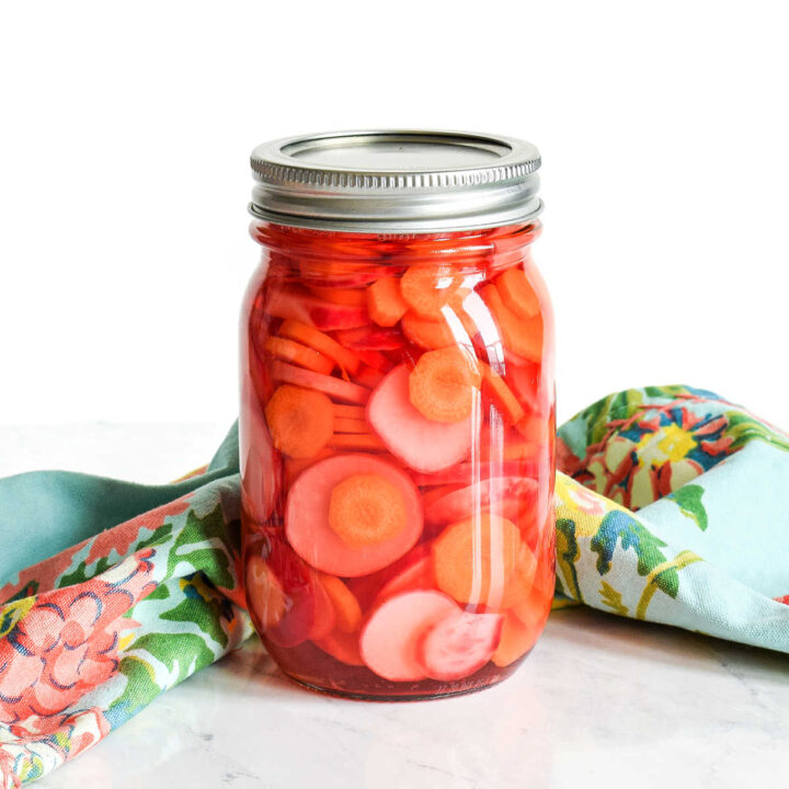 Pickled Carrots and Radishes served in a mason jar on a marble counter.