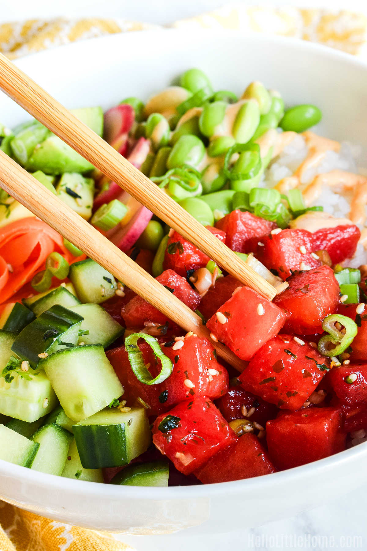 Chopsticks holding a piece of Watermelon Tuna over the vegetarian poke bowl.