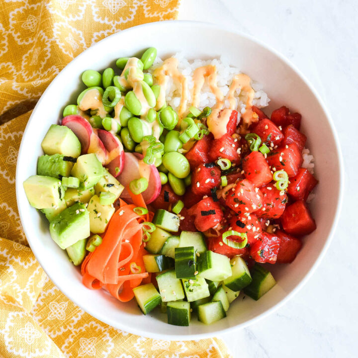 A Watermelon Poke Bowl served with a yellow napkin on a marble counter.