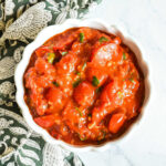 A bowl of Cherry Tomato Jam and a napkin on a marble counter.