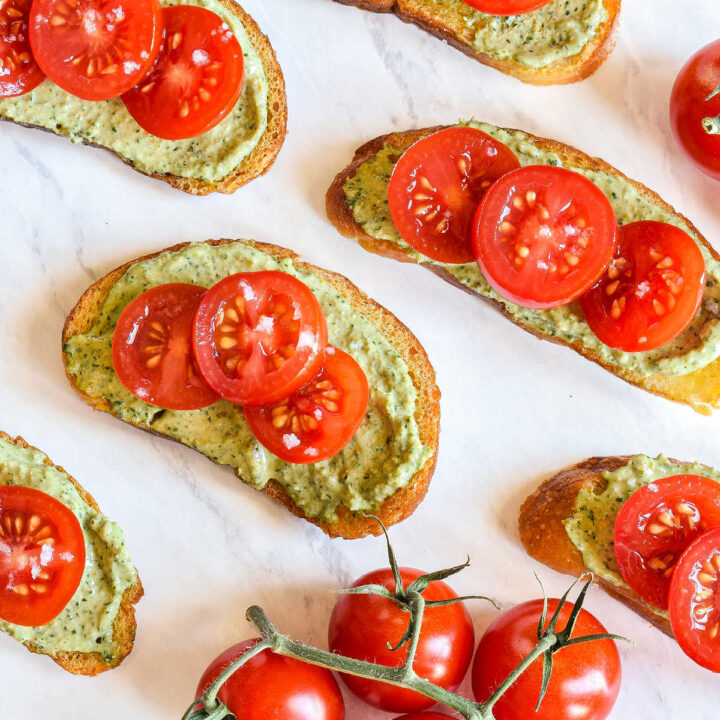 Pesto Ricotta Crostini served on a marble tray.