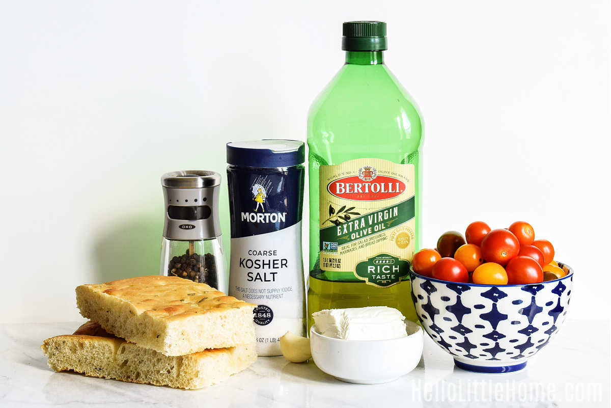 Roasted Tomato Crostini ingredients arranged together on a marble counter.