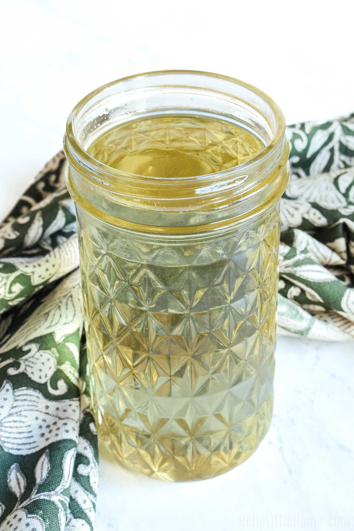 A open jar of the rosemary infused syrup and a napkin on a marble counter.