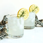 Two glasses of Rosemary Lemonade and a napkin on a marble counter.