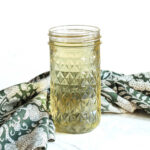 A jar of Rosemary Simple Syrup and a napkin on a marble counter.