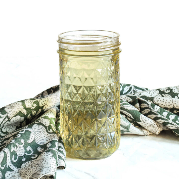 A jar of Rosemary Simple Syrup and a napkin on a marble counter.