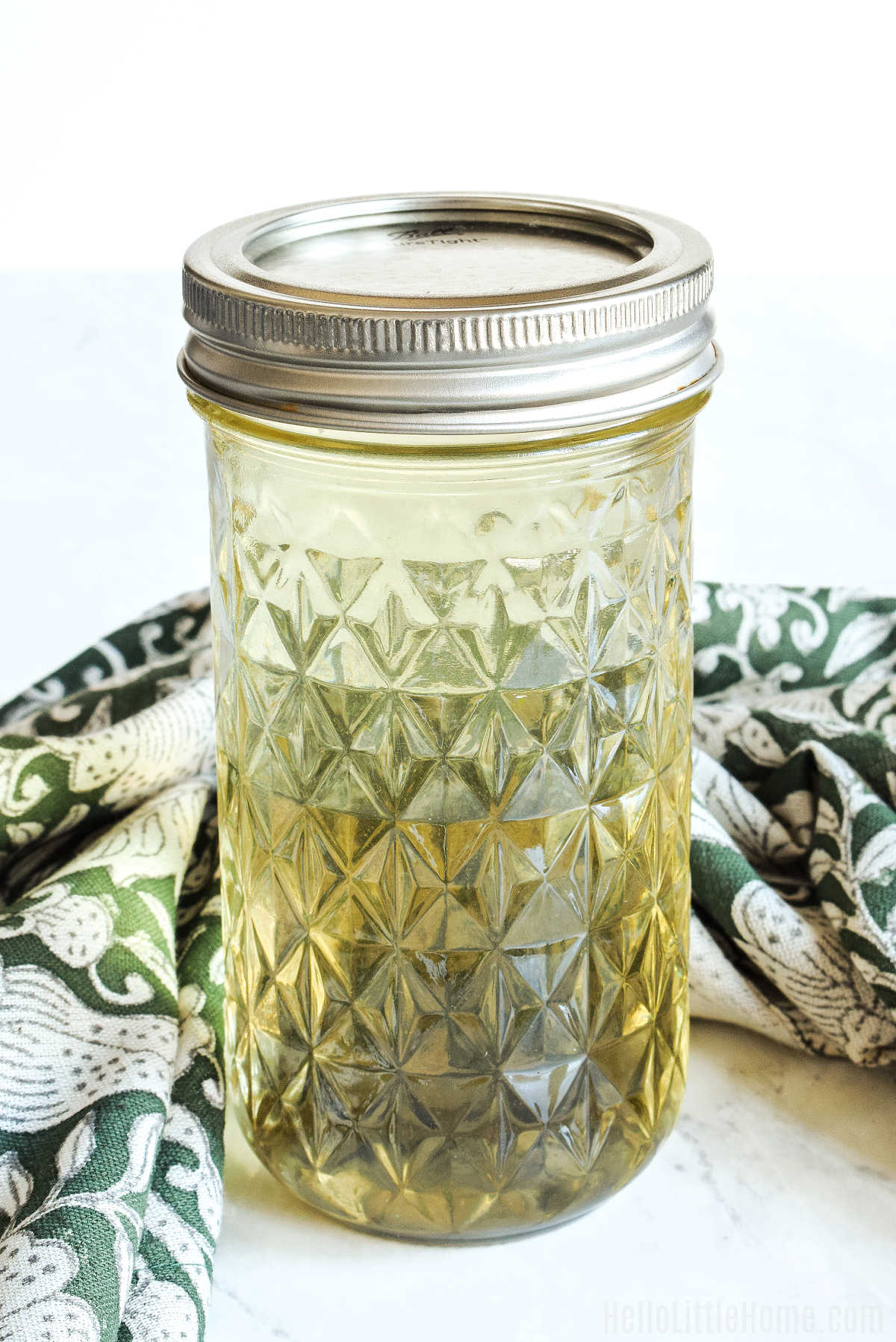 A jar of Rosemary Simple Syrup and a napkin on a marble counter.