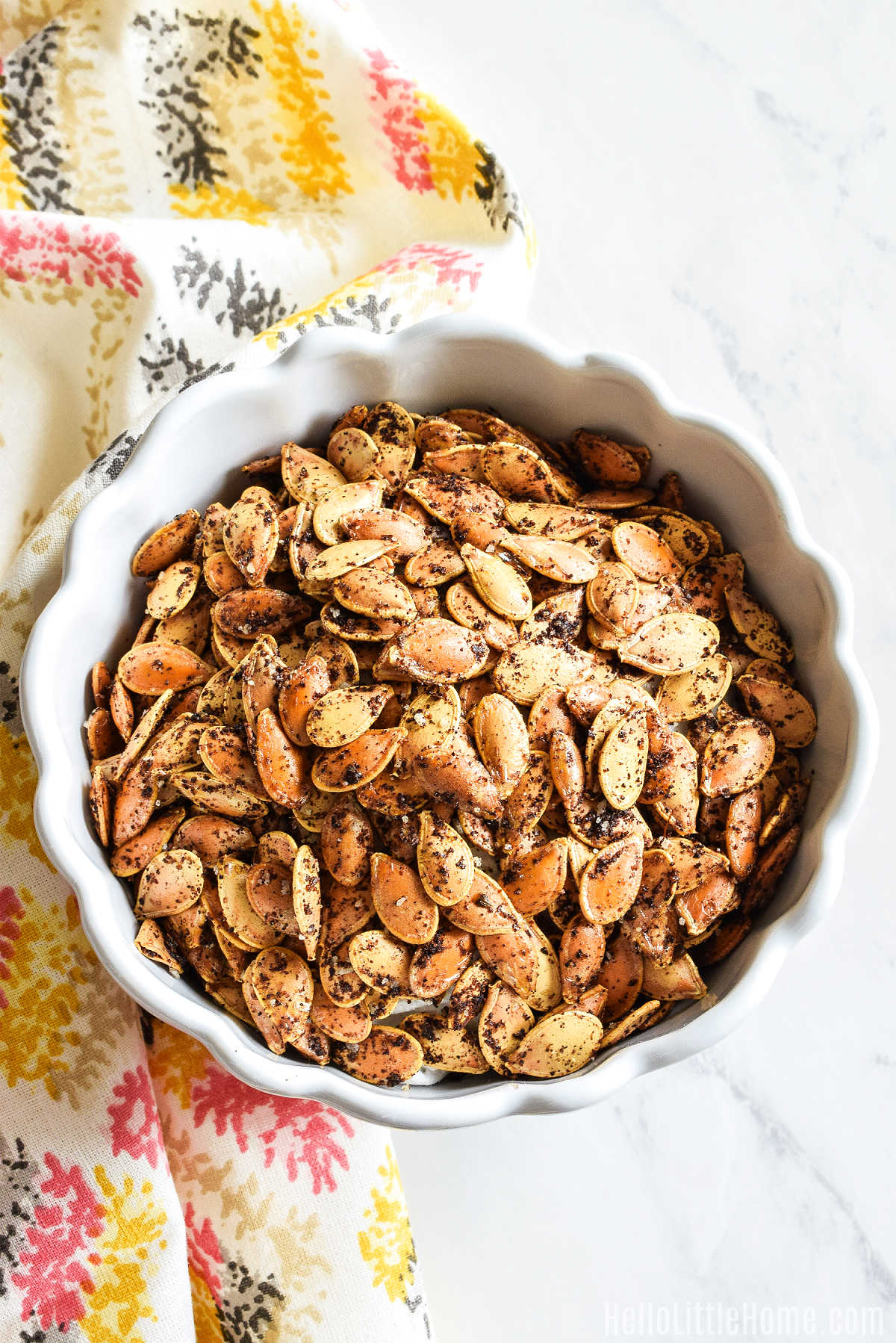 A bowl of the baked seeds and a napkin on a marble counter.