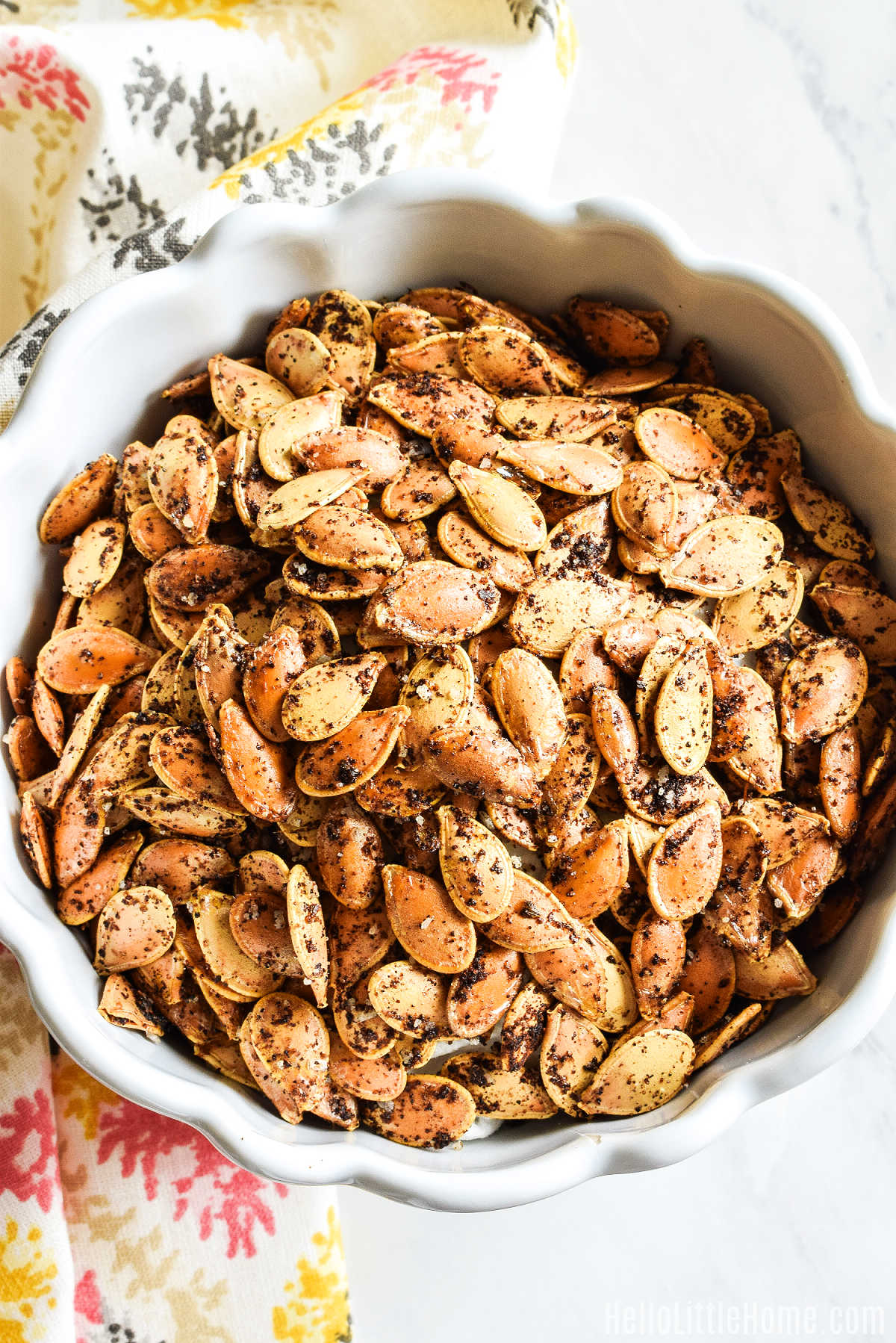 A bowl of homemade Cajun Pumpkin Seeds served with a patterned napkin.