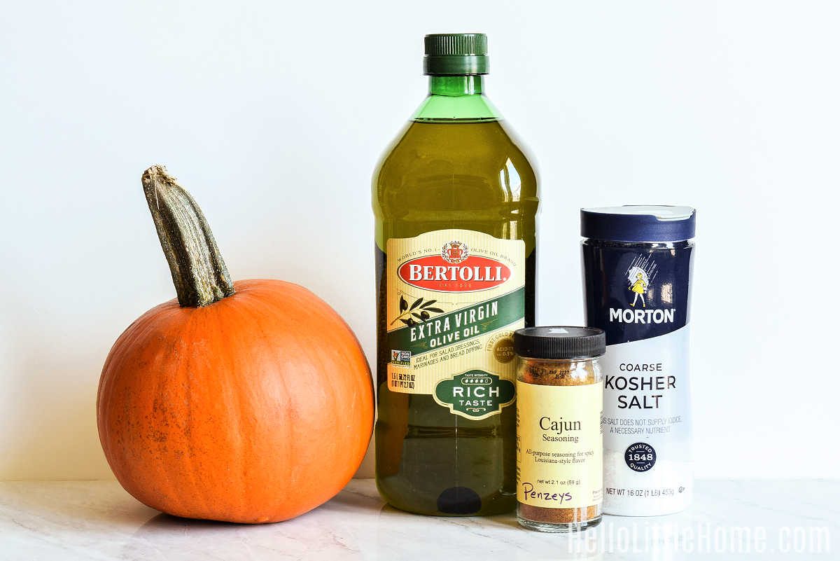 Ingredients for Cajun Roasted Pumpkin Seeds gathered together on a marble counter.