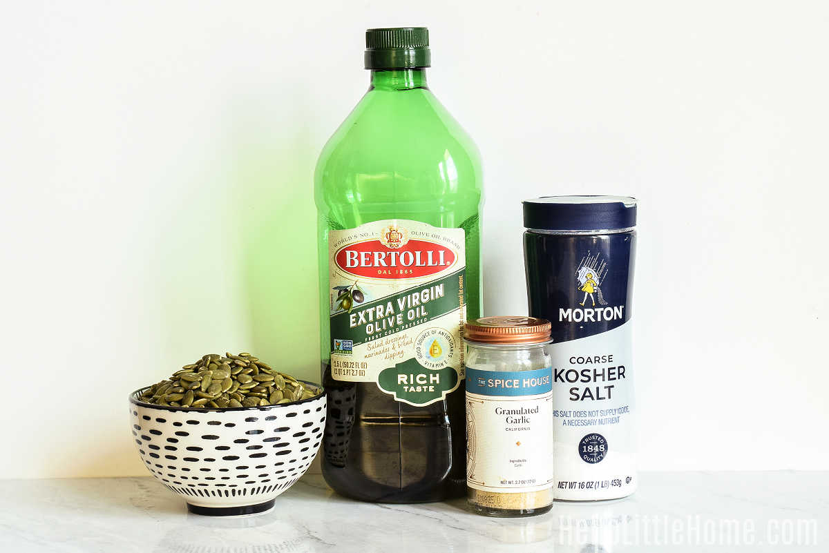 Ingredients for roasting pepita seeds gathered together on a marble counter.