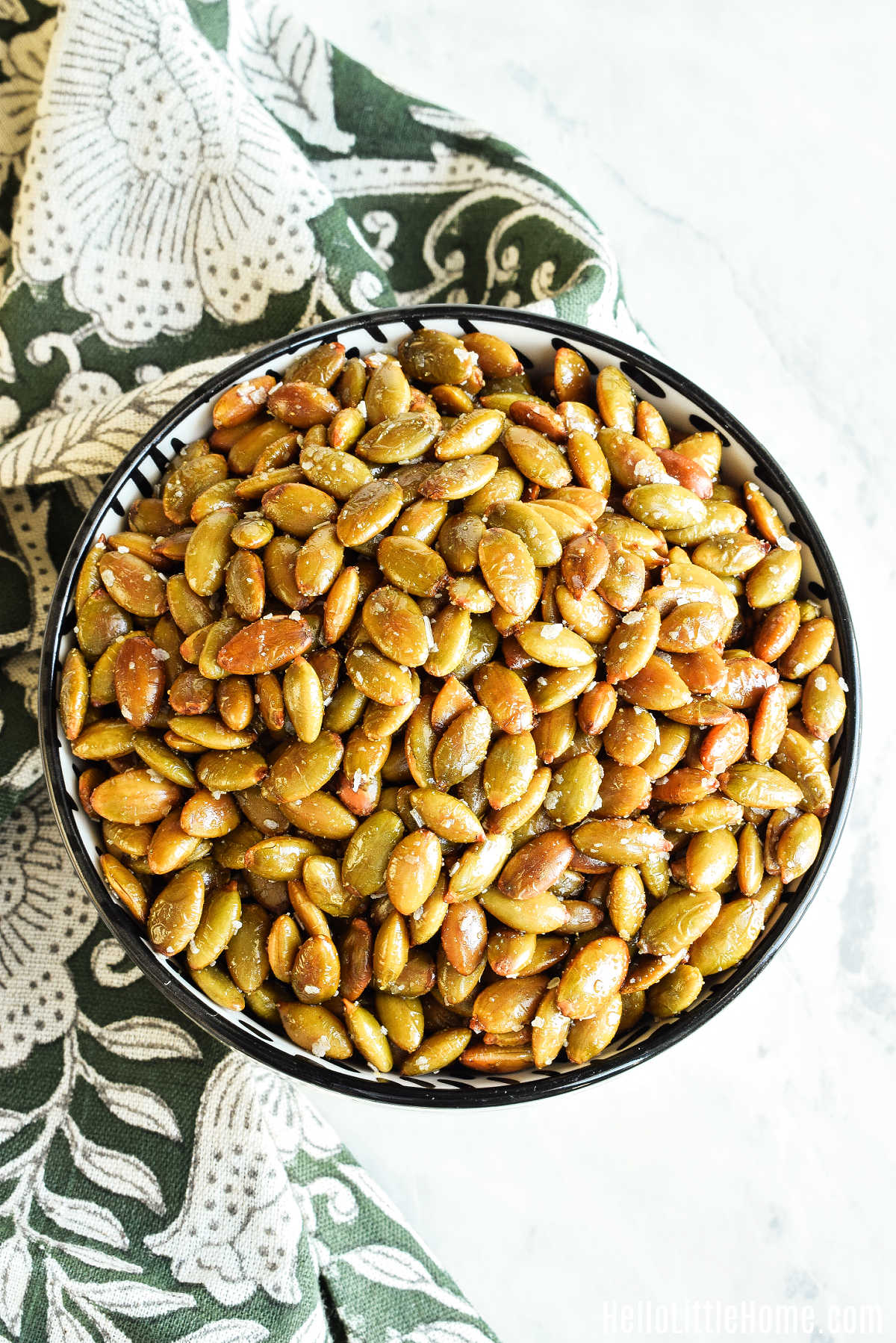 A bowl of Roasted Pepitas and a napkin on a marble counter.