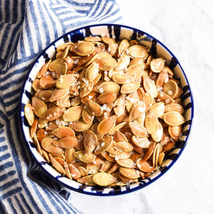 Salted Pumpkin Seeds served in a bowl with a striped napkin.