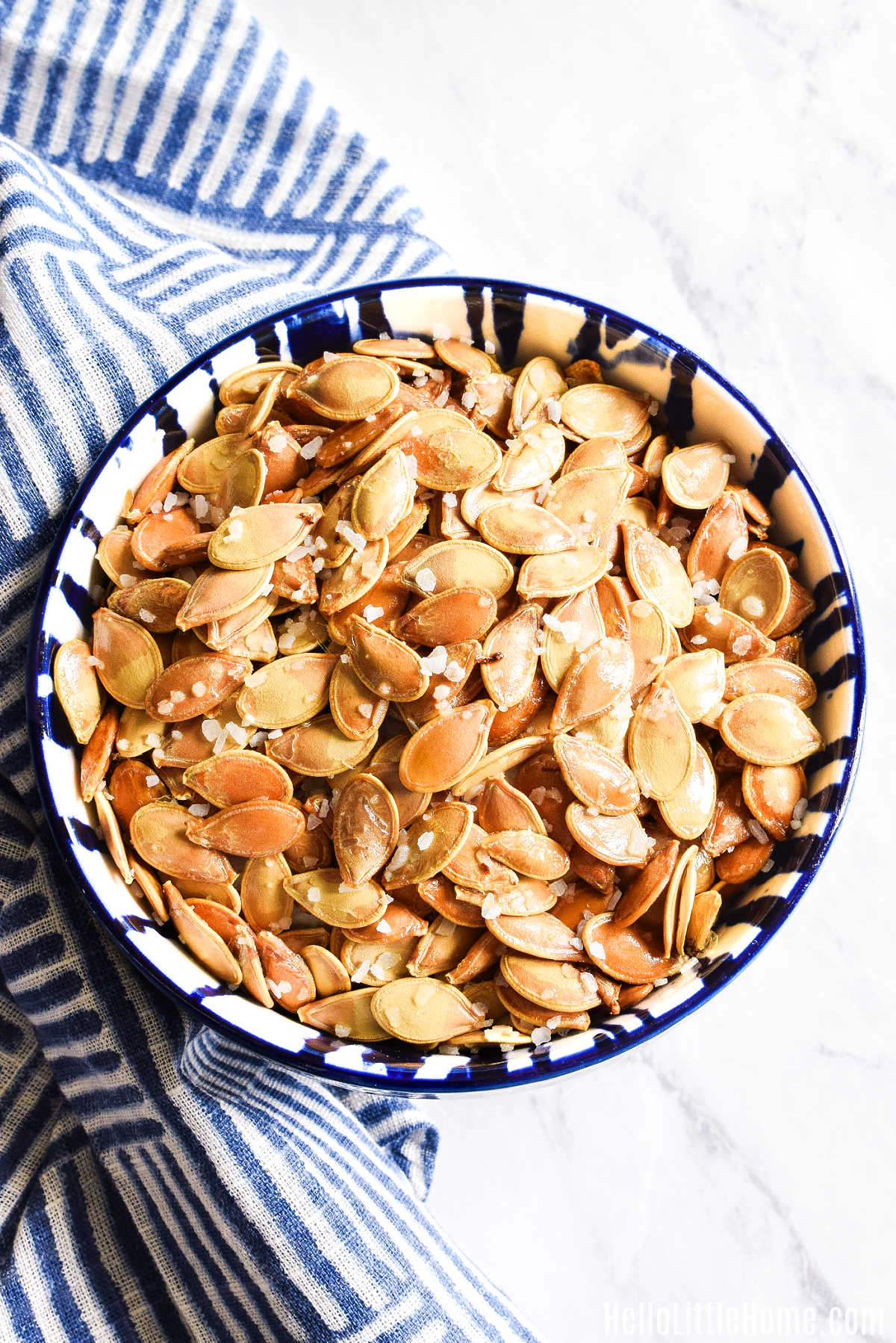A bowl of the baked seeds and a napkin on a marble counter.