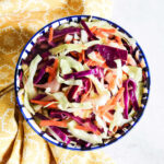 Homemade Taco Slaw served in a bowl next to a yellow napkin.